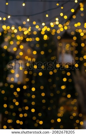 Blurred multicolored lights of a garland and branches of a Christmas tree in the foreground.Christmas and New Year background.Selective focus,copy space.