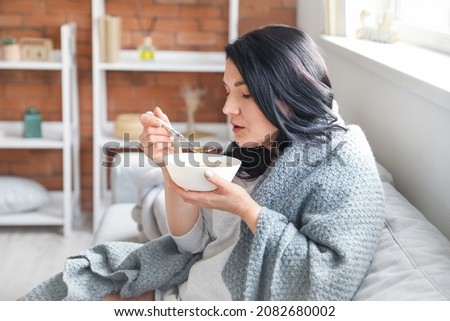 Sick mature woman eating chicken soup at home Royalty-Free Stock Photo #2082680002