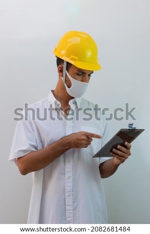 Worker with helmet and pandemic mask isolated on white background. Black man holding spread sheet.