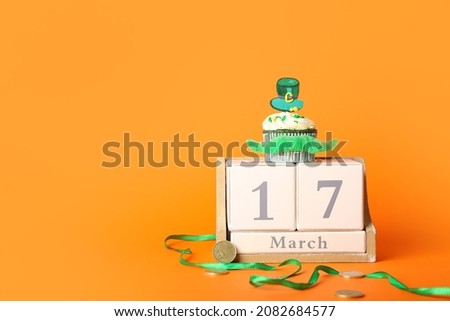 Tasty cupcake for St. Patrick's Day and calendar on color background