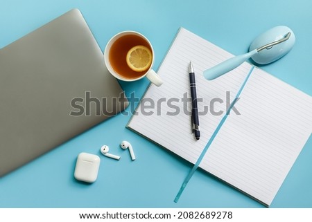 flatlay business, work from home, freelance, copywriting, top view laptop, notebook with blank pages and cup of tea on blue background. 