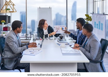 Woman manager is showing annual report chart to her African American colleagues in the executive meeting for next year plan with city skyline background for global business and investment Royalty-Free Stock Photo #2082705955