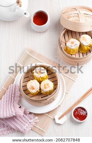 Shumai is traditional Chinese dumpling also known as dim sum, snack that made from prawn, chicken and mushroom. Served on bamboo steamer, with spicy chilli sauce.