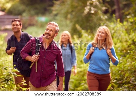 Mature And Mid Adult Couples In Countryside Hiking Along Path Through Forest Together Royalty-Free Stock Photo #2082708589