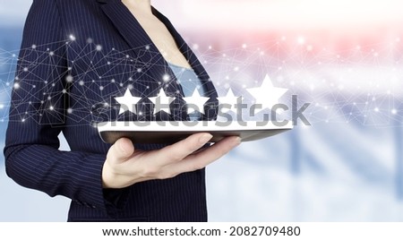 Five stars 5 rating with a hand touching screen. Hand hold white tablet with digital hologram five stars sign on light blurred background. Review, Rating,Satisfaction.