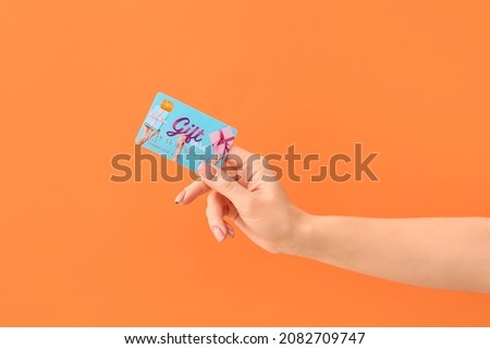 Female hand with gift card on color background Royalty-Free Stock Photo #2082709747