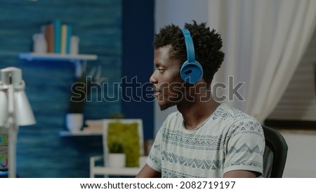 Graphic designer wearing headphones and retouching pictures on computer. Photographer doing editing work with software for photography project. Media editor working on photos retouch