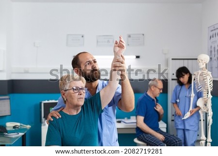Chiropractor holding arm of old woman to relieve pressure for recovery in osteopathy office. Orthopedic assistant helping senior patient with shoulder muscle pain for healthcare. Royalty-Free Stock Photo #2082719281
