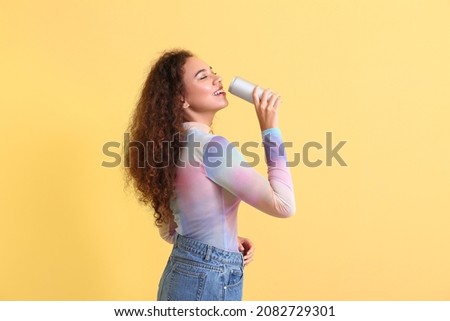 Beautiful African-American woman with soda on color background Royalty-Free Stock Photo #2082729301