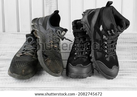 Close-up 2 pairs old and new black textile work boots for safe winter with steel toe,non-slip material sole on gray wooden background.Changing worn torn shoes to fresh,contrast concept.Selective focus Royalty-Free Stock Photo #2082745672