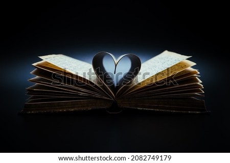 Music is the literature of the heart. It commences where speech ends. Opened antiquarian book with sheet music and pages curved into a heart shape.