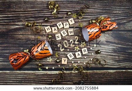 Banner. A symbol from the number 2022 with gold stars, sequins and a tiger-print firecracker on a wooden background. The concept of celebrating a Happy New Year and Christmas.