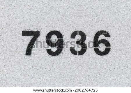 Black Number 7936 on the white wall. Spray paint. Number seven thousand nine hundred thirty six.