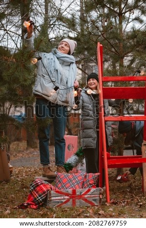 Two friends decorate Christmas trees before celebrating the new year 2022 outdoors for a party