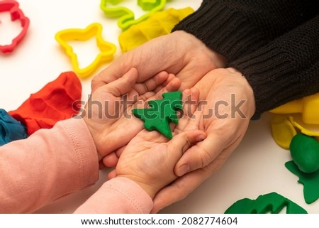 Girl playing dough with her mother. mother and daughter playing on white background. Making various shapes with dough. The girl gives the tree she made from dough to her mother. Close-up. Mothers DaY