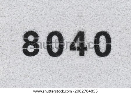 Black Number 8040 on the white wall. Spray paint. Number eight thousand forty.