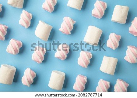 White and pink marshmallow on blue background. Pastel creative textured pattern. minimal. Top view