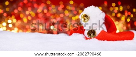 Santa Claus Hat in Snow on red blur Light. Christmas Background Decoration.