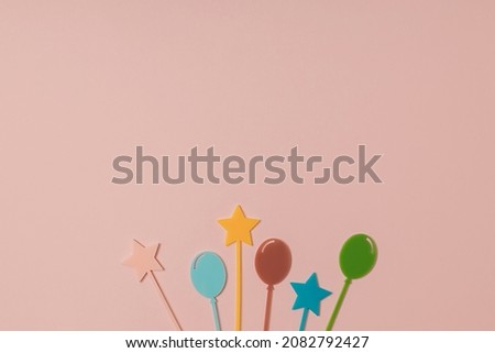Colourful cocktail cupcake picks star and balloon shaped on pastel pink background. Minimal Happy birthday flat lay. Celebration card or party concept. Holiday idea. Copy space. 