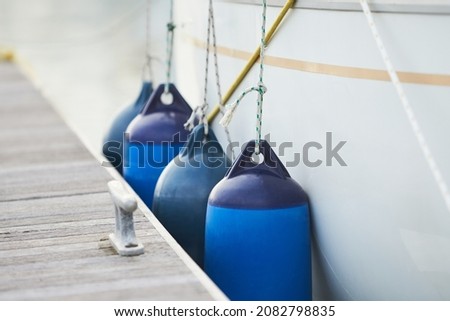 White fenders suspended between a boat and dockside for protection. Maritime fenders Royalty-Free Stock Photo #2082798835