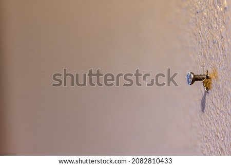 Macro of a single nail protruding from painted drywall in a residential house