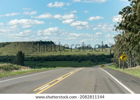 A lonely road and some hills on the background in Uruguay, next to Tacuarembó. The sky is full of small clouds and some trees on the right Royalty-Free Stock Photo #2082811144