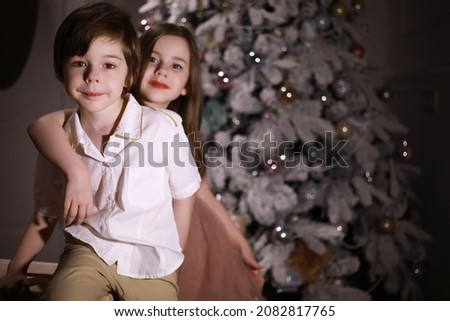 Child in smart clothes in front of the Christmas tree. Waiting for new year.