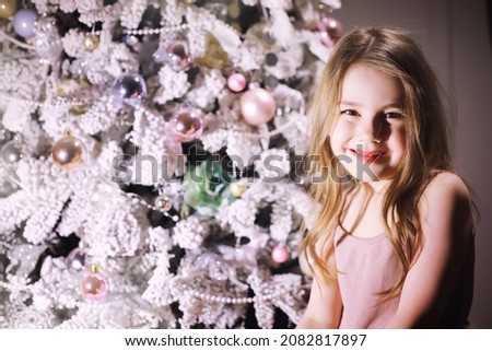Child in smart clothes in front of the Christmas tree. Waiting for the new year.