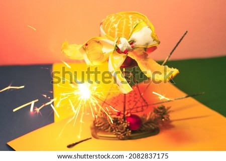 Funny New Year holiday celebration - fresh tangerine fruit with burning sparkling bengal fire