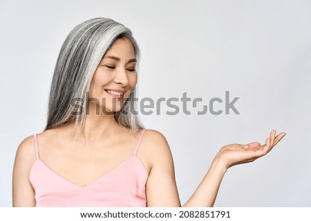 Middle aged happy mature asian woman, senior 50 year lady looking at copy space, isolated on white headshot. Ads of antiaging whitening menopause salon skincare treatments, plastic surgery. Royalty-Free Stock Photo #2082851791