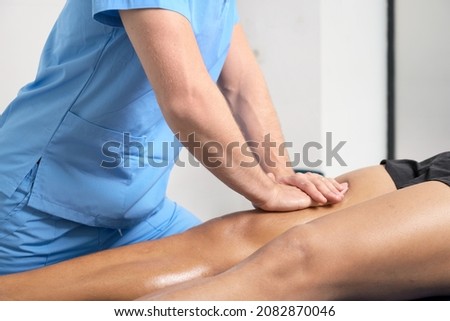 Close-up of therapist massaging young man's leg. High quality photo.