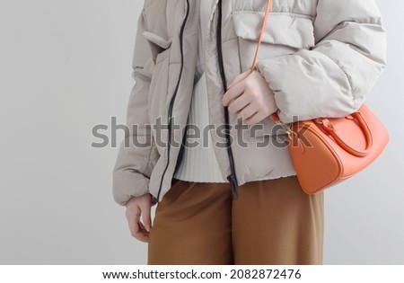 woman in  short down jacket with an orange handbag