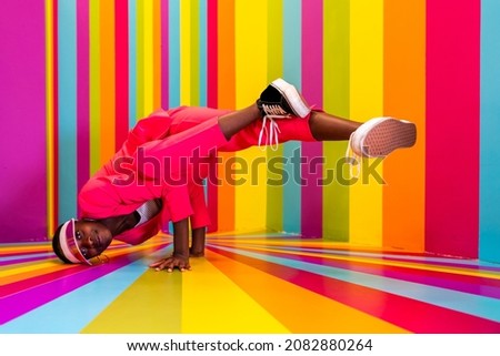 Beautiful african american young woman dancer having fun inside a rainbow box room - Cool and stylish adult woman portrait on multicolored background, influencer creating content for social networks Royalty-Free Stock Photo #2082880264