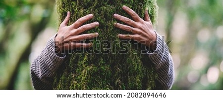 Nature lover hugging trunk tree with green musk in tropical woods forest. Green natural background. Concept of people love nature and protect from deforestation or pollution or climate change Royalty-Free Stock Photo #2082894646