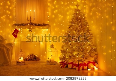 Christmas Tree Interior with Golden Lights Decoration in White Room with Fireplace and Candles. Xmas Decorated Fir Tree with Gift Boxes