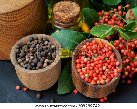 Black peppercorns, pink peppercorns in a composition with herbs and olive oil. Close-up