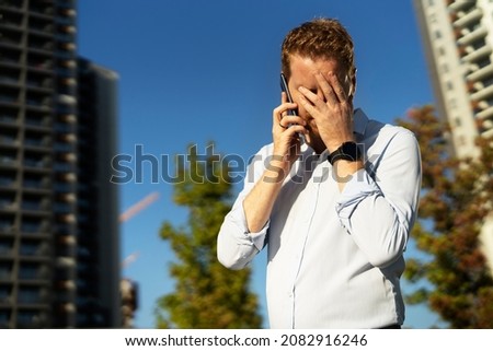 Upset businessman outdoors. Angry man talking to the phone