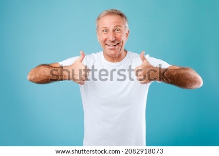 I Recommend. Portrait of excited senior man showing thumbs up sign gesture with both hands, approving something good, great offer. Happy adult male standing posing on blue studio background