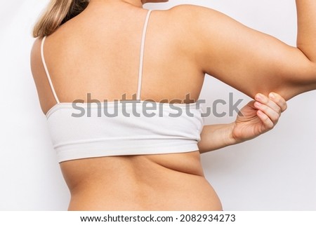 Excess weight on the upper body. Cropped shot of a young woman grabbing skin on her upper arm with excess fat isolated on a white background. The loose and saggy muscles of a back and arms. Overweight Royalty-Free Stock Photo #2082934273