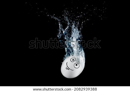 Funny smiling chicken egg character dropped into water with splashes isolated on black background