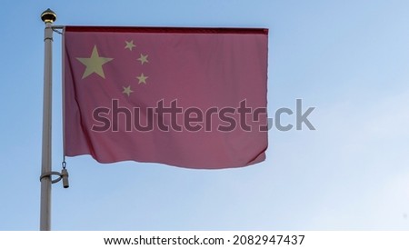 National flag of China on a flagpole in front of blue sky with sun rays and lens flare. Diplomacy concept. International relations. Space for text.