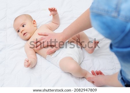 A caring mother gives her baby son a tummy massage and helps to get rid of colic. Royalty-Free Stock Photo #2082947809
