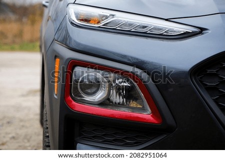 headlight of modern prestigious car closeup. beautiful headlights of a car. dark gray color, red edging. part of the front. direction indicators on a sports car. macro photo. front view