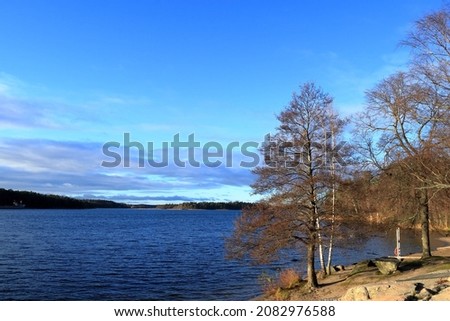 Nice view over a Swedish lake during the autumn of November 2021. Calm and clear weather, mostly blue sky. Hässelby, Stockholm, Sweden, Scandinavia, Europe.