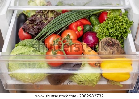 Vegetable compartment of the refrigerator full of fresh vegetables. Open fridge, drawer filled with fresh vegetables.