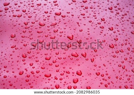Close up picture of rain drops on red car hood