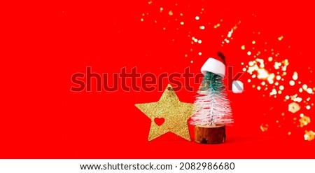 Gold star and decorative Christmas tree in santa claus hat on red background. Christmas decor. Creative copy space. Close-up