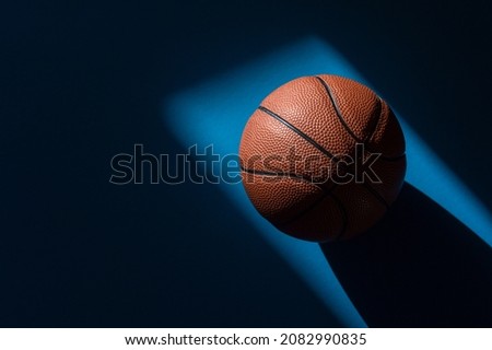 Brown new basketball ball with natural lighting on blue background. Sport team concept. Horizontal sport theme poster, greeting cards, headers, website and app
