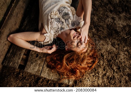 girl with red hair posing near wooden house