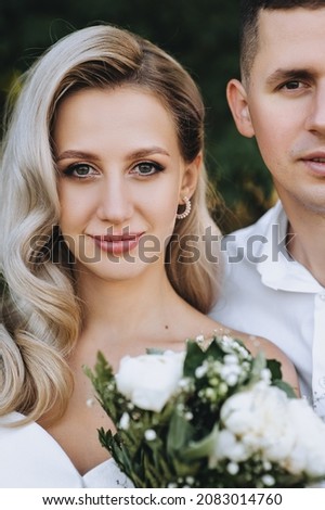 Wedding portrait, close-up photo of half faces of beautiful blonde bride with curly hair and stylish groom.